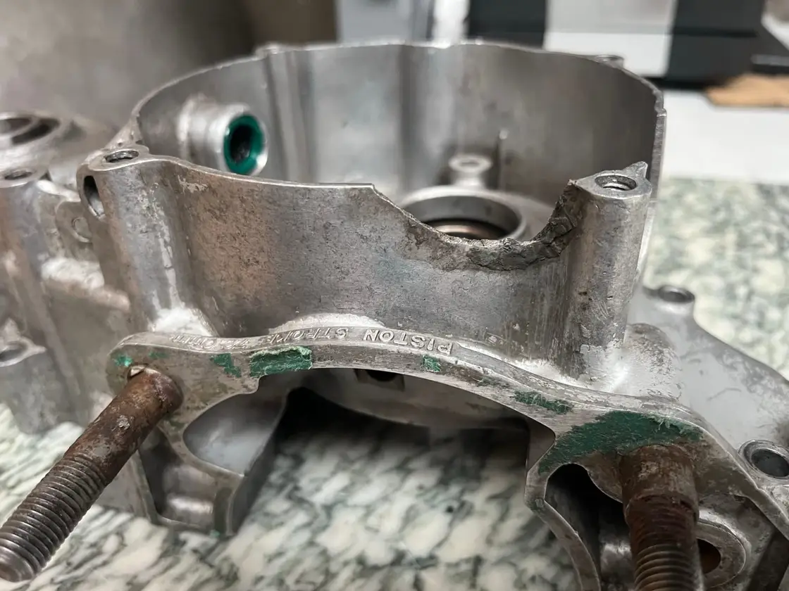 Carter moteur de moto en aluminium : bord arraché autour du logement de roulement, avant réparation